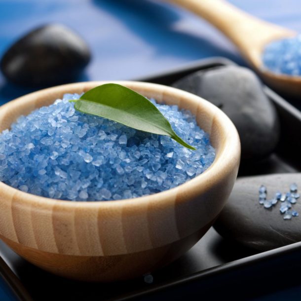 Closeup of blue crystals or salt with rocks and leaves.