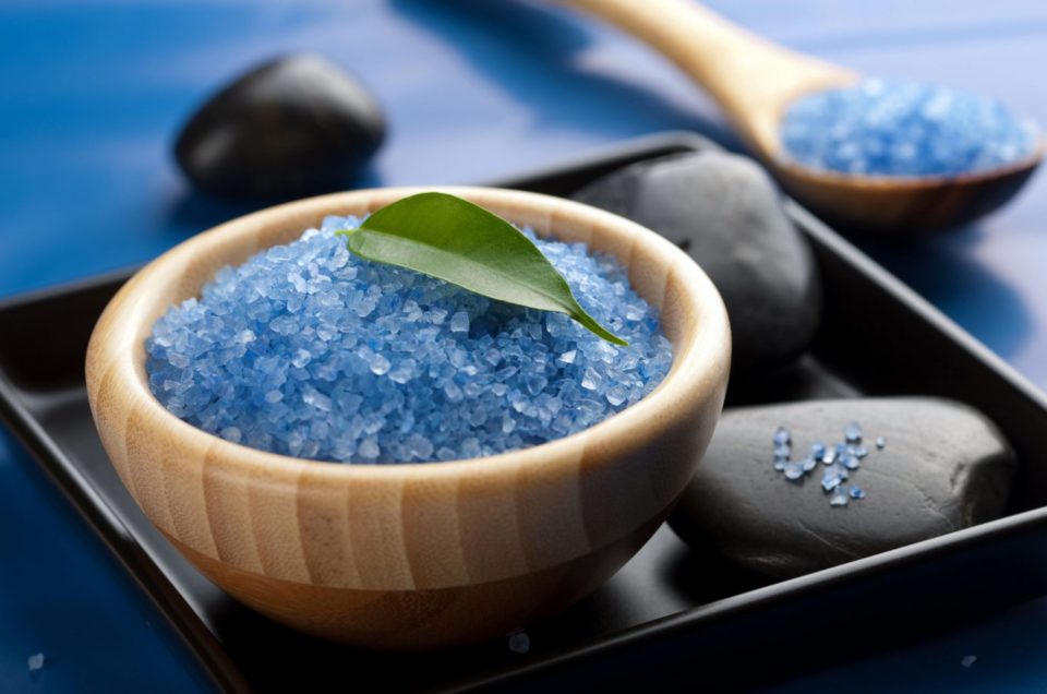 Closeup of blue crystals or salt with rocks and leaves.