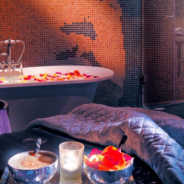 Massage bed and bath with candles on flower petals.