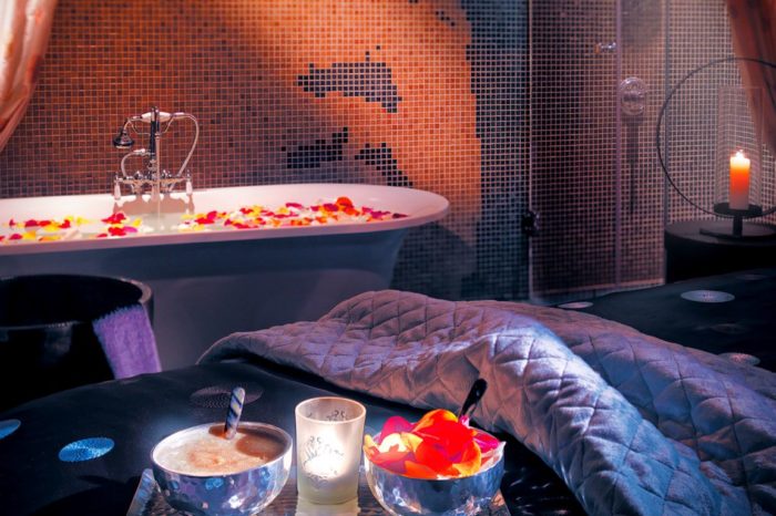 Massage bed and bath with candles on flower petals.