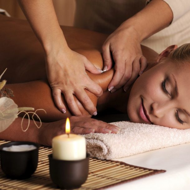 Young woman receiving a massage next to aromatics and candles.