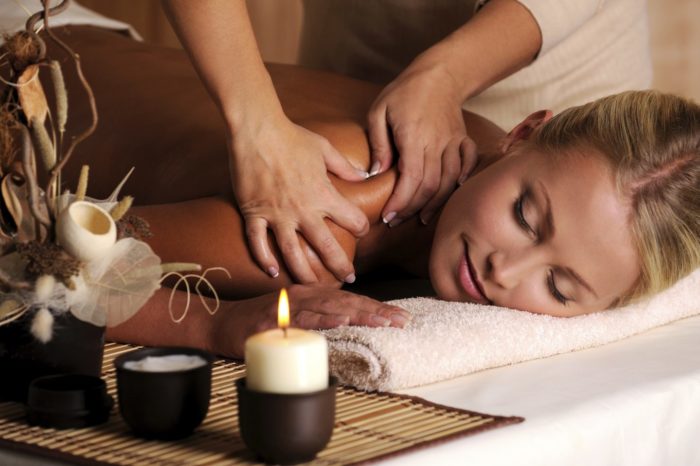 Young woman receiving a massage next to aromatics and candles.