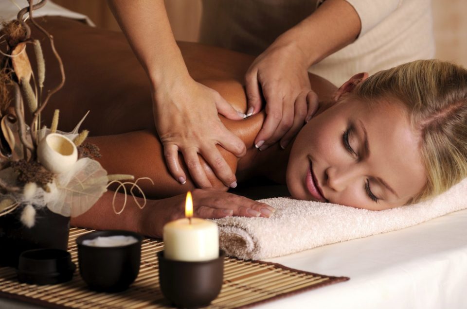 Young woman receiving a massage next to aromatics and candles.
